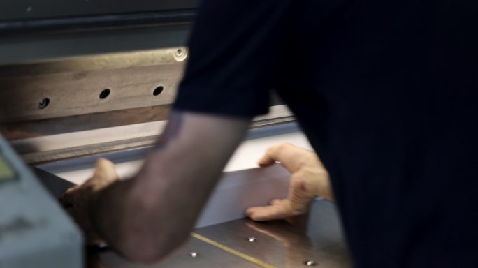 无法识别的白人工人在印刷厂，在CNC切割机上切割一捆纸