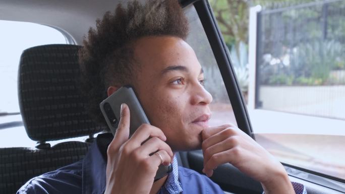一位年轻的商人坐在上班的汽车乘客座上打电话