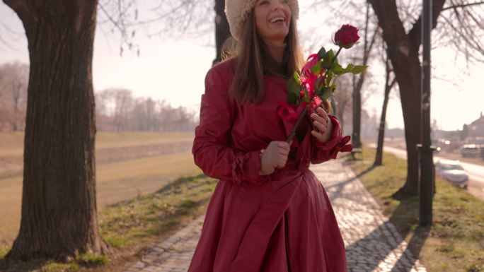 穿着红色外套的女人手里拿着一朵玫瑰