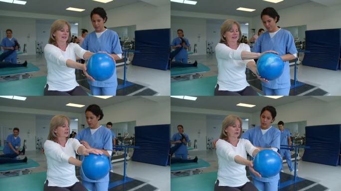 女性老年患者按照治疗师的指示，用球锻炼双手、手臂和肩膀
