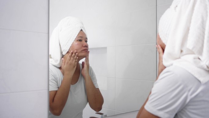 女人在镜子上检查脸上的皮肤