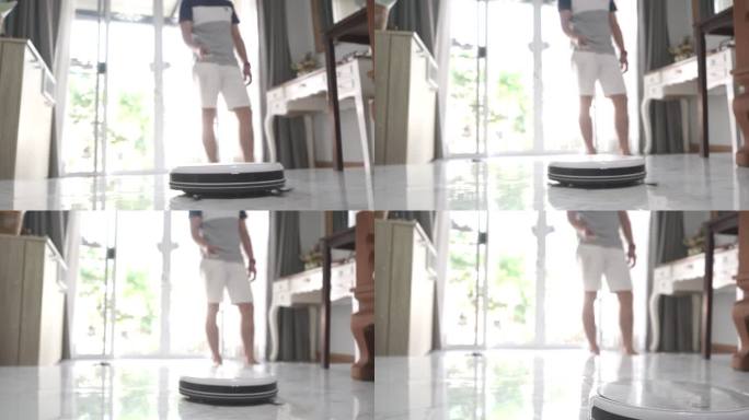 男人在家里用智能手机控制智能机器人吸尘器