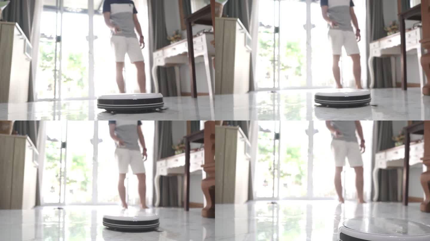 男人在家里用智能手机控制智能机器人吸尘器