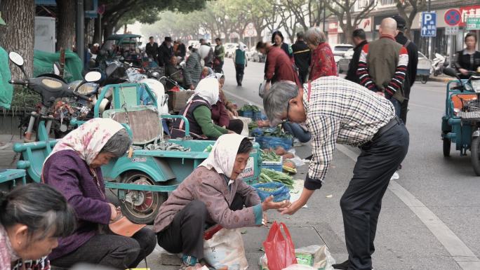 清晨古镇老街上农民在临时菜市场卖菜