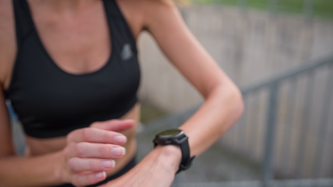 女性慢跑者跑上楼梯，最后用智能手表查看时间
