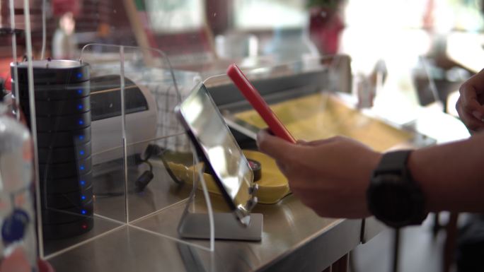 顾客在咖啡厅柜台酒吧使用手机支付无接触平板电脑。