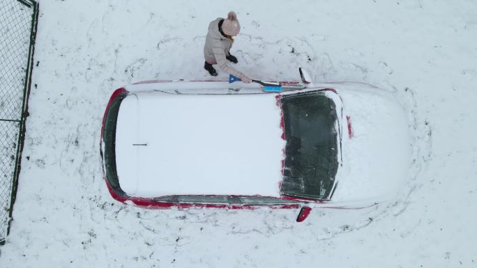 穿着冬季夹克的人从车窗上刮冰雪