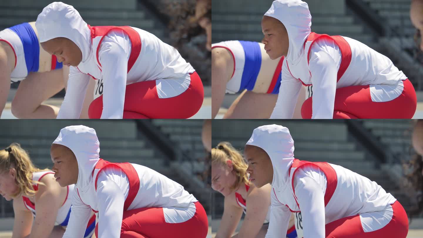 戴着头巾的女子田径运动员在起跑线上准备