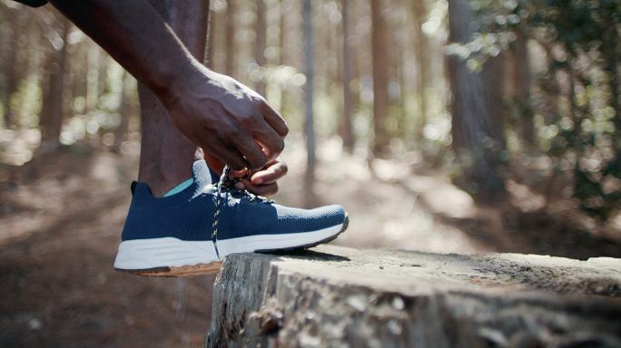 一个无法辨认的男子系鞋带，在森林中慢跑的4k视频片段