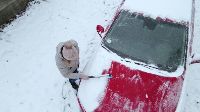 女人从车上除雪立冬小雪大雪冬至汽车上积雪