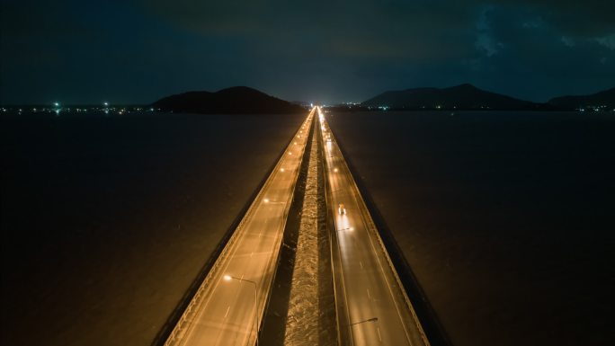 空中无人机超时差或时差夜以继日交通车在横跨松克拉湖的桥上的场景，Tinsulanonda桥。沿着横跨
