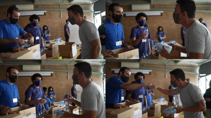 志愿者在慈善捐赠中心问候男子-戴防护口罩