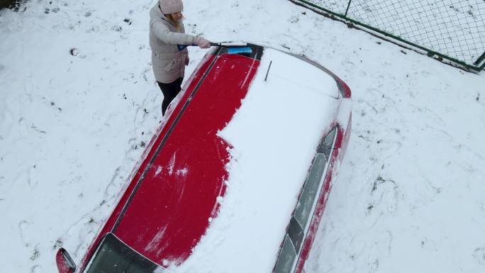 一个女人在雪中清洗她的车