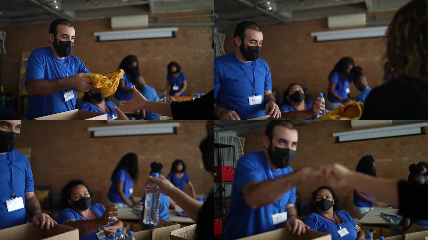 志愿者在慈善捐赠中心向一名妇女捐赠衣服-戴着防护口罩-包括一名残疾人