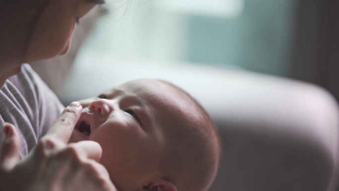 亚裔中国母亲在家里与刚学步的男婴亲密接触，用嘴唇与他交谈