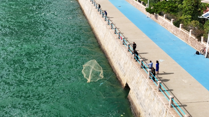 航拍青岛海滨城市海钓撒网