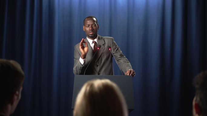 一位非裔美国政治家在辩论中发表演讲，听众为他鼓掌