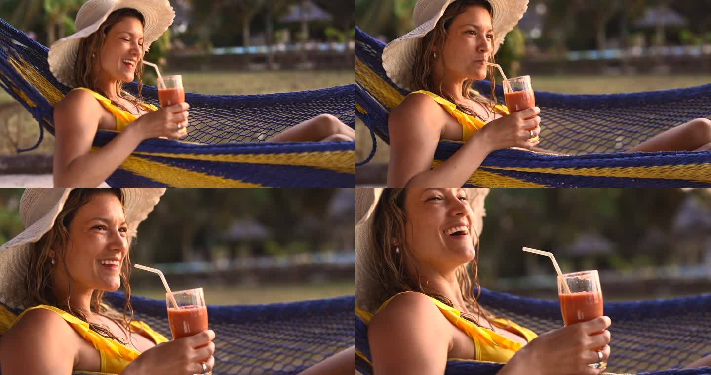 快乐的女人在夏日在吊床上喝冰沙。