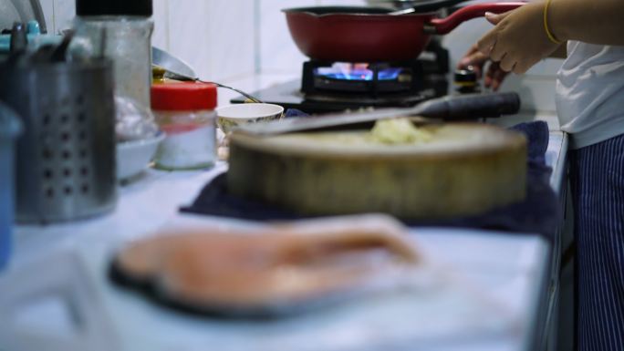 女性烹饪和三文鱼在厨房货架焦点