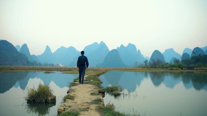 中国桂林，一位背着背包的男性游客在稻田上行走