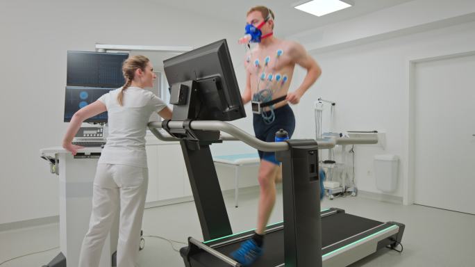 年轻的男性运动员在诊所的跑步机上做心肺压力测试