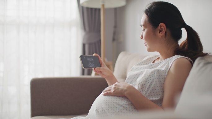 孕妇在手机上观看她的宝宝的超声波视频