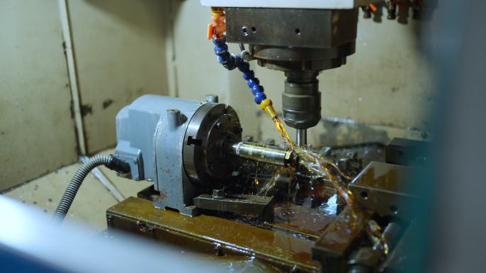 特写的钢刮削机成型另一块钢连接到数控主轴杆。有刮痕，小油管正在冷却钻头。制造工厂背景
