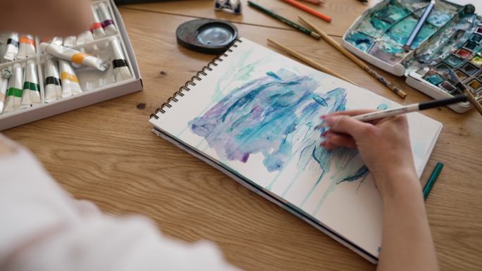 艺术家用水彩画，坐在家里的桌子上特写