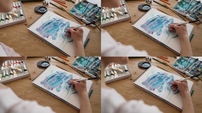 艺术家用水彩画，坐在家里的桌子上特写