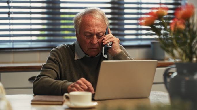 一名老年人在家使用笔记本电脑时打手机的4k视频片段