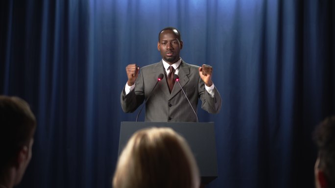 穿着灰色西装的年轻非裔美国政治家在辩论中情绪化地发表演讲