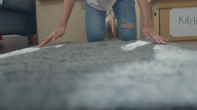 一位年轻的亚洲女性卷起地毯搬进新房子的特写镜头。