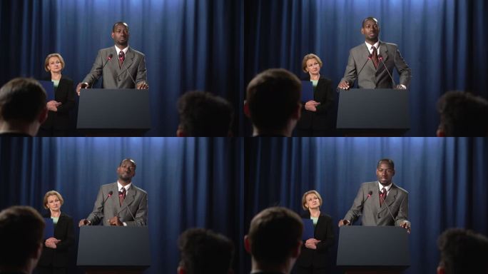 一位身穿灰色西装的非裔美国政治家在辩论中发言时解释了一些事情