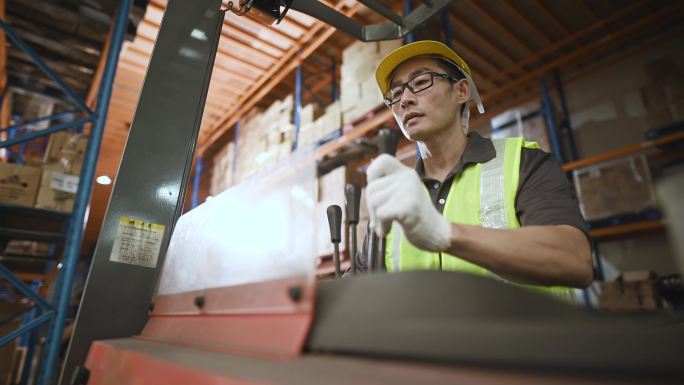 亚裔中国仓库工人在工业工厂操作叉车