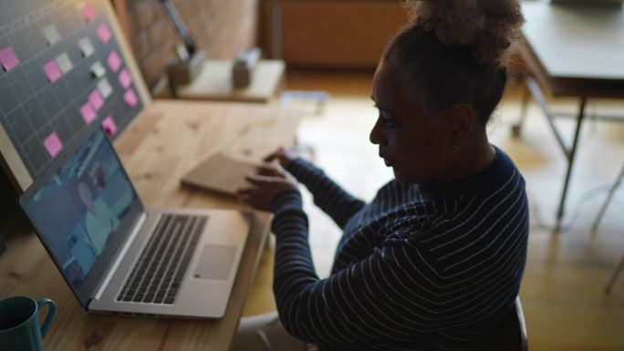 一位资深女性在工作中用笔记本电脑进行视频通话