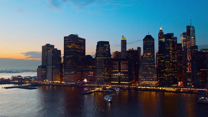 东河对面曼哈顿下城的鸟瞰图，在夕阳的暮色中照亮。无人机视频与平移相机运动。