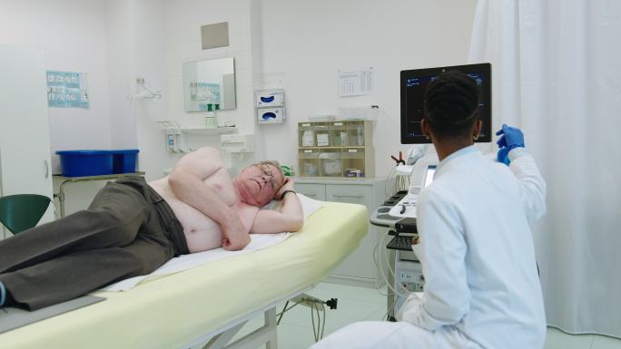 女性医学专业人员为成年男性做心脏超声检查