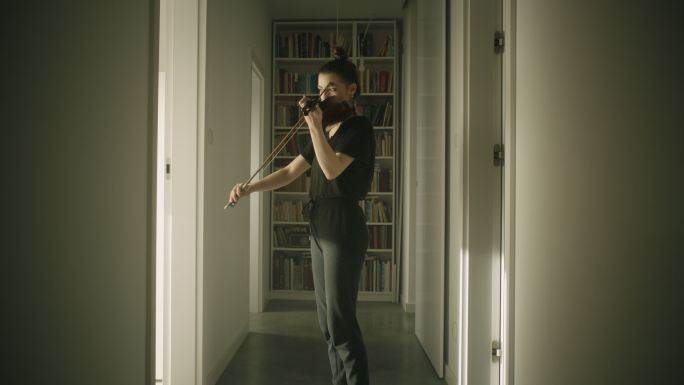 美丽的年轻女子音乐家在走廊里拉小提琴