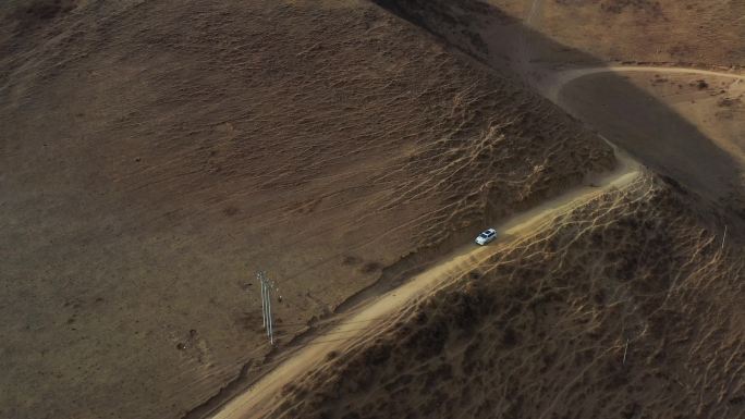 航拍越野车行驶在高原草甸半山腰的公路上