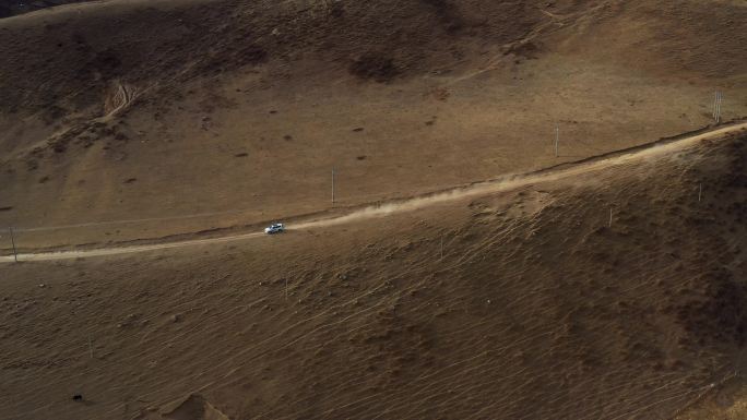 航拍越野车行驶在高原草甸半山腰的公路上