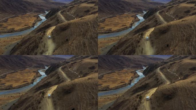 航拍越野车行驶在高原草甸半山腰的公路上