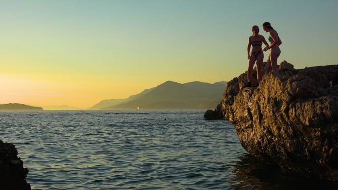 日落时分，克罗地亚海岸的青少年从悬崖上跳下，游回杜布罗夫尼克附近的海岸