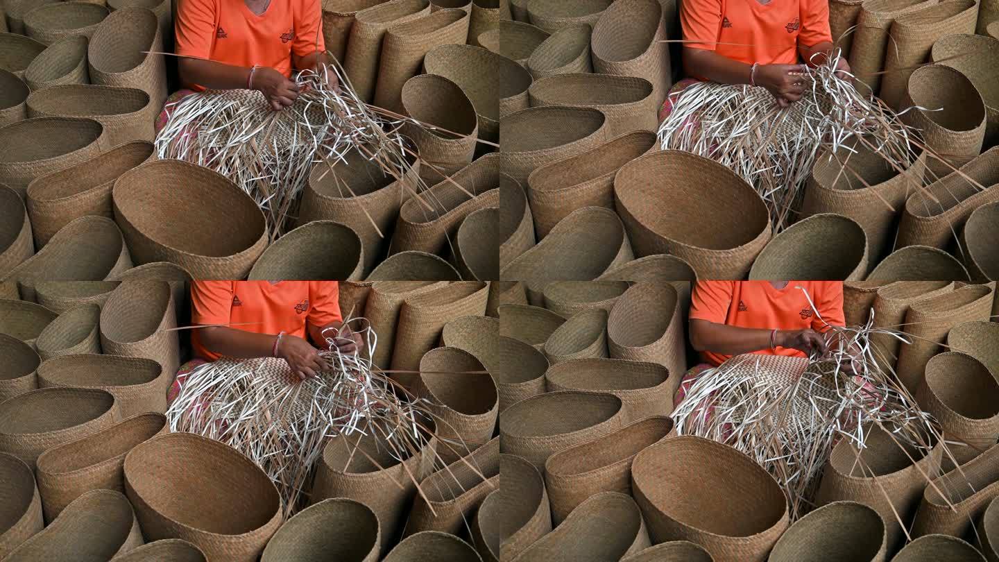 特写妇女编织干树叶编织篮子的手，手工制作篮子