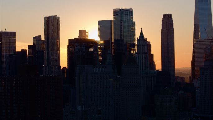 曼哈顿下城的天际线，日落时的轮廓映衬着天空。带有摇摄相机运动的空中镜头。