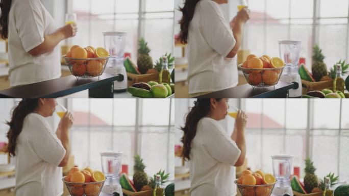 亚洲成熟女性准备在厨房里把水果切成小块，用橙子自制冰沙。