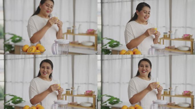 亚洲成熟女性准备在厨房里把水果切成小块，用橙子自制冰沙。