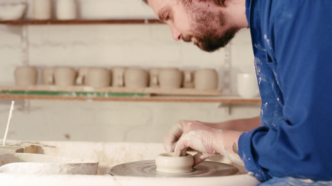男性陶工在他的工作室里雕刻陶瓷艺术。技艺精湛的工匠享受着自己的爱好，制作手工艺品在创业企业中出售。一