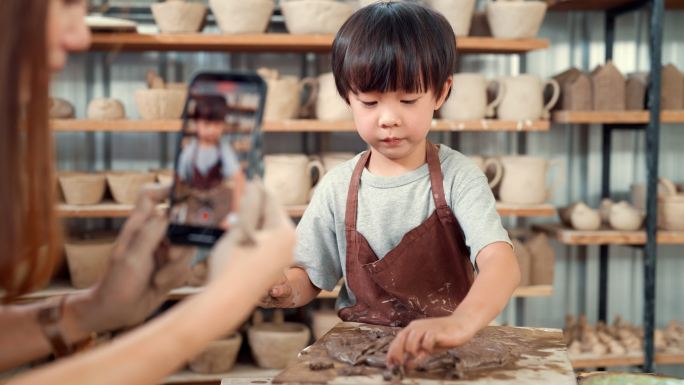 母亲和儿子一起在车间里做陶瓷制品。