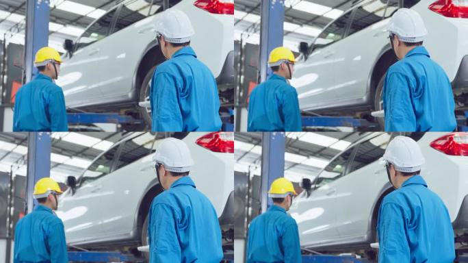 亚洲两名汽车修理工戴着头盔在修理厂工作。车辆服务经理团队的男性工人检查车况，检查并维护车间的发动机