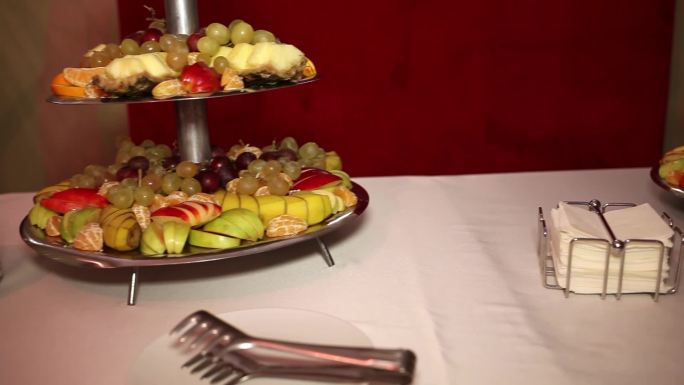 多层托盘上的混合水果。展示的水果包括葡萄、西瓜、菠萝、甜瓜、酸橙等